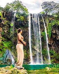 a tourist enjoying beautiful view of lush valley with waterfall